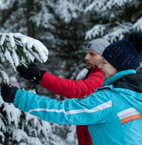 Nainen ja mies koskevat lumista kuusen oksaa