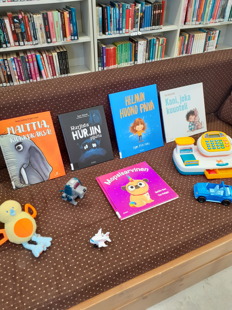 Kuvassa näkyy leluja ja lastenkirjoja sohvalla.