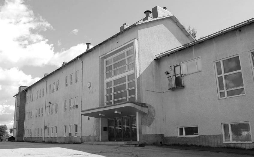 Mustavalkoinen kuva, jossa näkyy kolmekerroksinen koulurakennus. Kuvan koulurakennus on nyt jo purettu kirkonkylän koulu Rautavaaran kirkonkylällä.