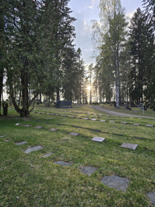 Kuvassa Rautavaaran sankarihautausmaan haudat. Kaukana ilta-aurinko laskeutuu.