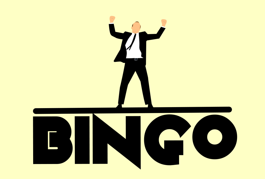 Kuvassa pukupäinen mies tuulettemassa. Hänen allaan lukee teksti "BINGO".